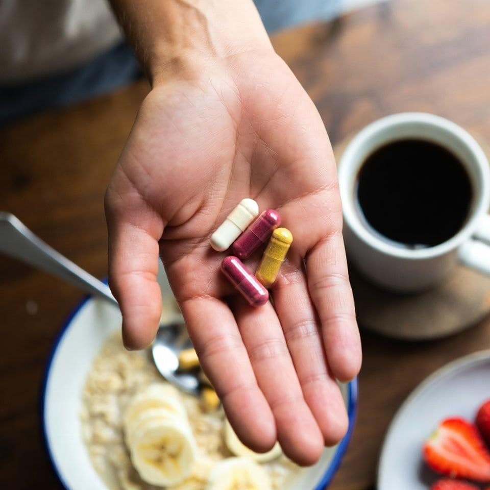 hand-holding-supplement-capsules-breakfast The Morning Supplement Stack for Focus and Energy